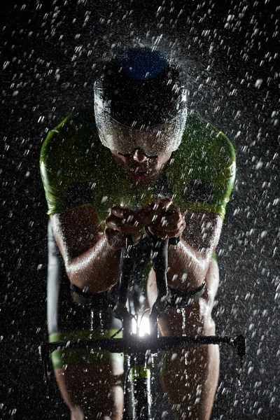 Triatlon atleet rijden fiets snel op regenachtige nacht — Stockfoto