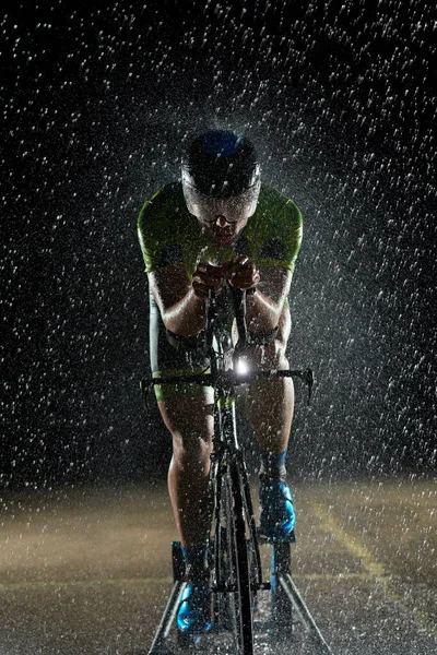 Triatlon atleet rijden fiets snel op regenachtige nacht — Stockfoto