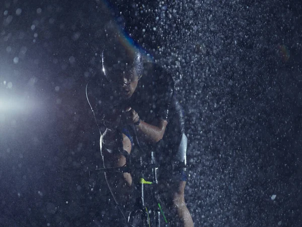 Triathlon athlète vélo d'équitation sur la nuit pluvieuse — Photo