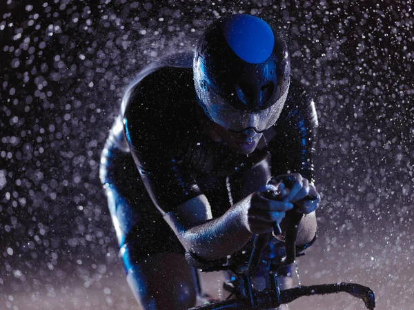 Yağmurlu bir gecede bisiklet süren triatlon sporcusu — Stok fotoğraf