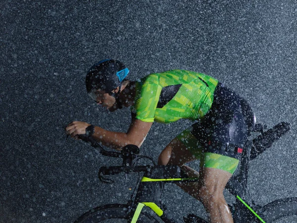 雨の夜に自転車に乗るトライアスロン選手 — ストック写真