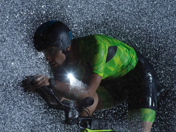 Triatlón atleta montar en bicicleta en la noche lluviosa — Foto de Stock