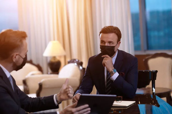 会議でクロナウイルス対策フェイスマスクを身に着けているビジネスマンは — ストック写真