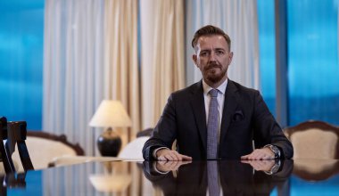 Modern ofiste şık bir takım elbiseyle gülümseyen CEO portresi.