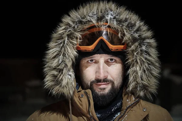 Άντρας το χειμώνα σε θυελλώδη νύχτα φορώντας ζεστό γούνινο μπουφάν — Φωτογραφία Αρχείου