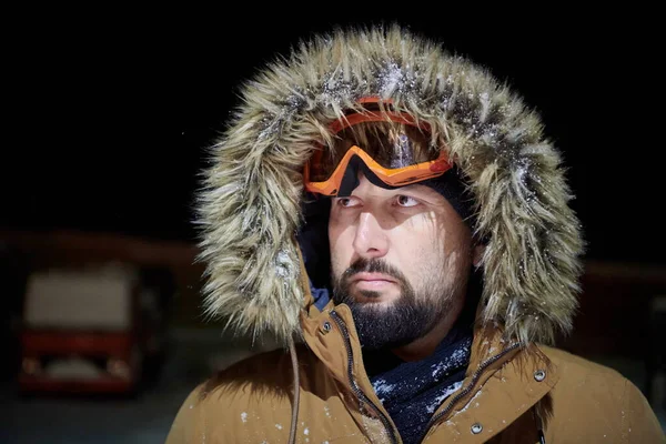 Άντρας το χειμώνα σε θυελλώδη νύχτα φορώντας ζεστό γούνινο μπουφάν — Φωτογραφία Αρχείου