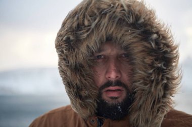 Kışın fırtınalı havada sıcak kürk ceket giyen bir adam.