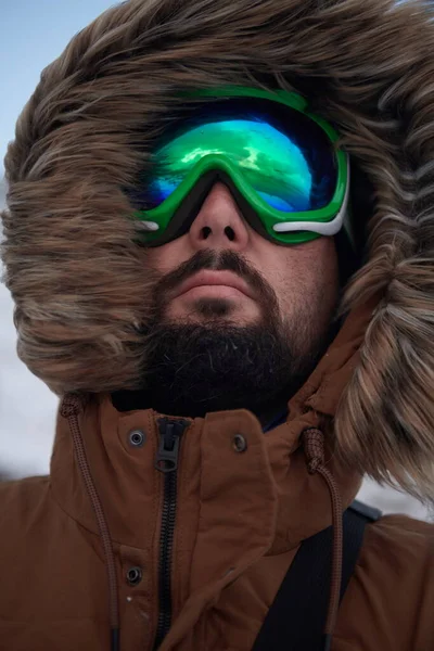 Человек зимой в бурную погоду в теплой меховой куртке — стоковое фото