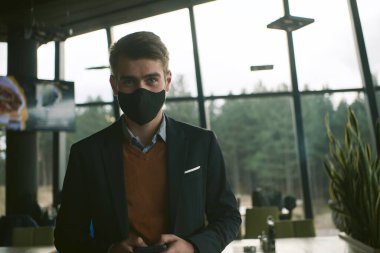 Lüks ofiste koruyucu yüz maskesi takan bir iş adamı.