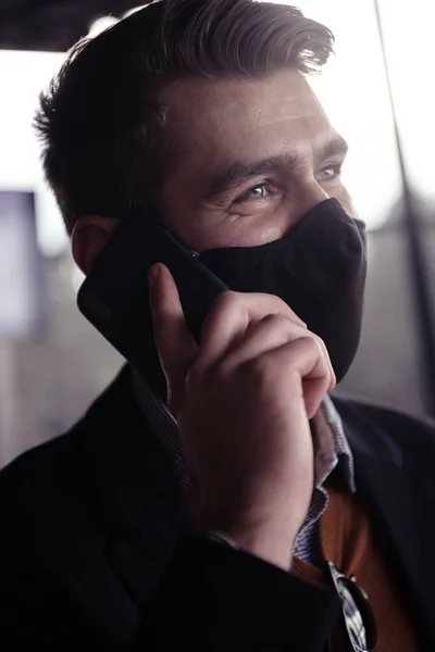 Üzletember visel coronavirus orvosi arc maszk használata közben smartphone — Stock Fotó