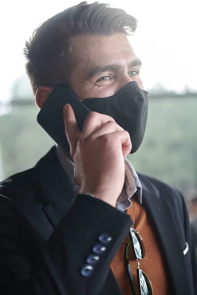 Zakenman draagt coronavirus medisch gezichtsmasker tijdens het gebruik van smartphone — Stockfoto