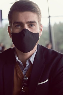 Lüks ofiste koruyucu yüz maskesi takan bir iş adamı.
