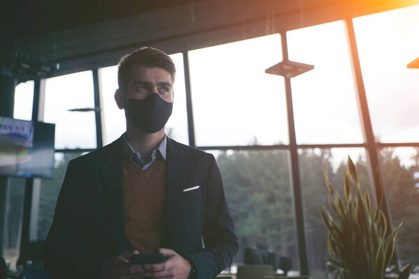 Corporate businessman wearing protective medical face mask at modern open space office concept of new normal in business