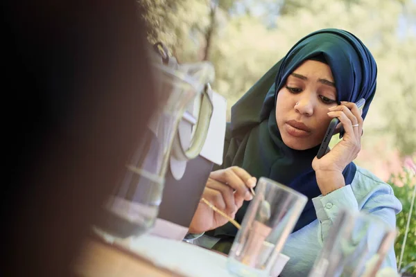 アフリカの女性は伝統的なイスラム教徒の服を着てスマートフォンを使い — ストック写真