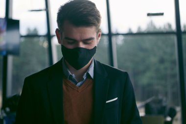 Lüks ofiste koruyucu yüz maskesi takan bir iş adamı.