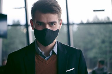 Lüks ofiste koruyucu yüz maskesi takan bir iş adamı.