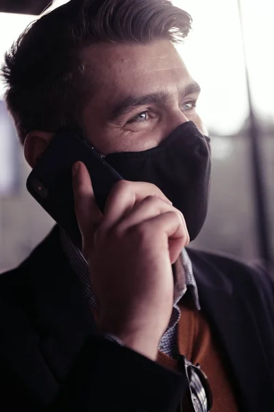 스마트폰을 사용하면서 코로나 바이러스 의료 마스크를 쓰고 있는 사업가 — 스톡 사진