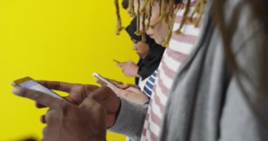 Cep telefonu kullanan çok kültürlü bir arkadaş grubu. Öğrenciler sıraya girip renk duvarının üzerinden akıllı telefonlara yazı yazıyorlar.