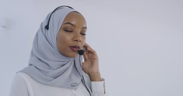 Afrikansk muslim kvinna med hijab halsduk kundrepresentant affärskvinna med telefon headset hjälpa och stödja online med kunden i moderna ljusa callcenter isolerad på vit bakgrund — Stockvideo