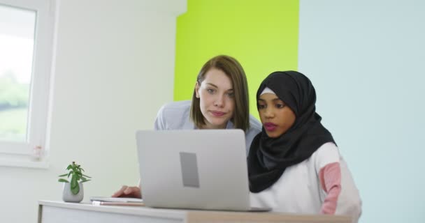 Diversità Incontro delle donne etniche In carica. Ragazza sorridente in Hijab che lavora sul computer portatile, bionda che guarda lo schermo. — Video Stock