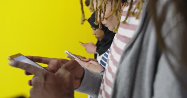 Grupo multicultural de amigos usando celulares - Estudantes de pé em uma fileira e digitando nos smartphones sobre a parede de cores — Vídeo de Stock