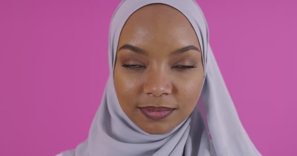 プラスチックピンクの背景に伝統的なイスラム教徒の服を着て若い現代のイスラム教徒アフロの美しさのショットを閉じます — ストック動画