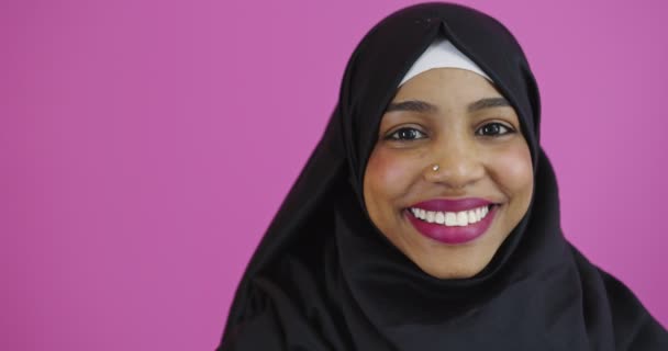 Ung vacker afrikansk amerikansk flicka bär muslim hijab över färgglada bakgrund ler och skrattar, positiv muslim kvinna — Stockvideo
