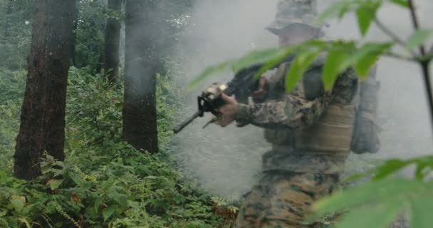Żołnierz poruszający się przez las smokey z karabinem gotowy do strzału, biegnący przez las podczas akcji wojskowej — Wideo stockowe