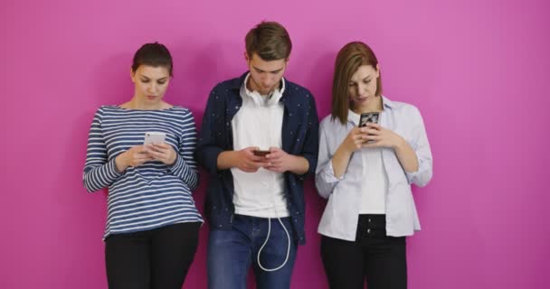 Estudiantes sobre fondo colorido utilizando teléfonos celulares, divertirse y enviar un mensaje — Vídeos de Stock
