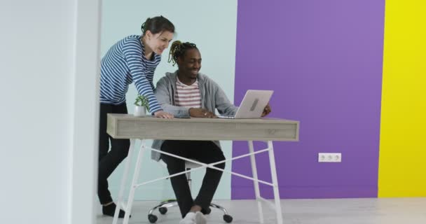 Pria dan wanita tersenyum positif di dekat tempat kerja dengan laptop yang bekerja sama di kantor — Stok Video