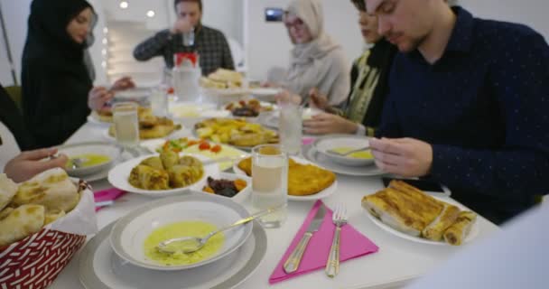 Familia musulmana de Eid Mubarak cenando con Iftar tomando fotos con teléfono móvil mientras come comida tradicional durante el mes de fiesta del Ramadán en casa — Vídeo de stock