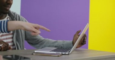 İş yerinin yakınında laptopla iş birliği yapan gülümseyen bir adam ve kadın.