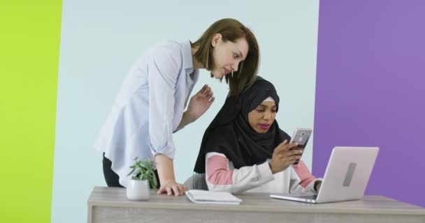Různorodost Etnické setkání žen v úřadu. Usmívající se dívka v hidžábu pracuje na notebooku, blondýny při pohledu na obrazovku. — Stock video