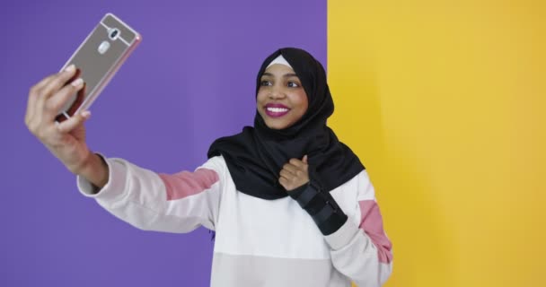 Mulher árabe feliz no hijab com telefone celular fazendo selfie sobre fundo de cor — Vídeo de Stock