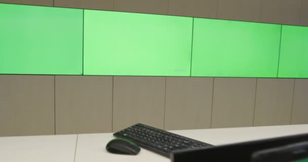 Специалист по системной безопасности работает в центре системного управления. Комната заполнена зелеными экранами, цветным экраном и системой безопасности — стоковое видео