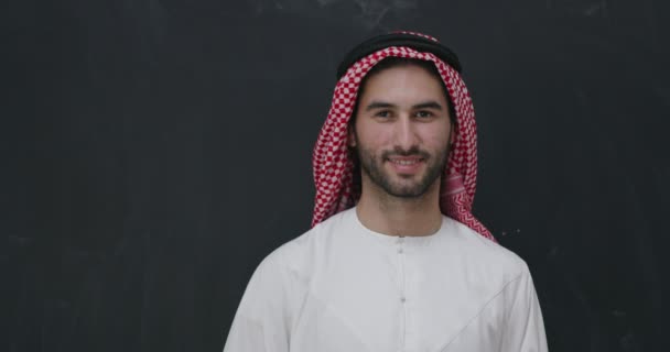 Portrait of young arabian man in traditional clothes in front of black chalkboard — Stock Video