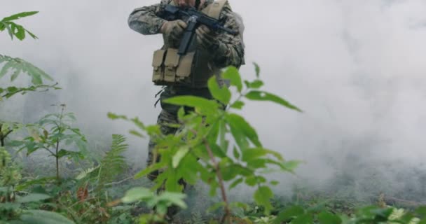 Soldat bewegt sich mit schussbereitem Gewehr durch verrauchten Wald und läuft während eines Militäreinsatzes durch Wald — Stockvideo