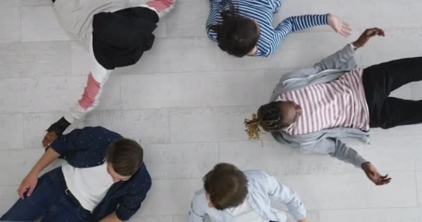 Многоэтническая группа друзей в кругу, лежащая на полу — стоковое видео