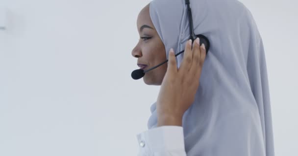 Afrikanische Muslimin mit Hijab-Schal Kundenvertreterin Geschäftsfrau mit Telefon-Headset hilft und unterstützt online mit Kunden in modernen hellen Call Center isoliert auf weißem Hintergrund — Stockvideo