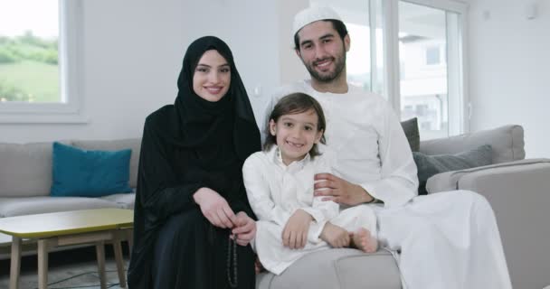 ソファの上で子供と一緒に伝統的なイスラム教徒の家族の親 — ストック動画