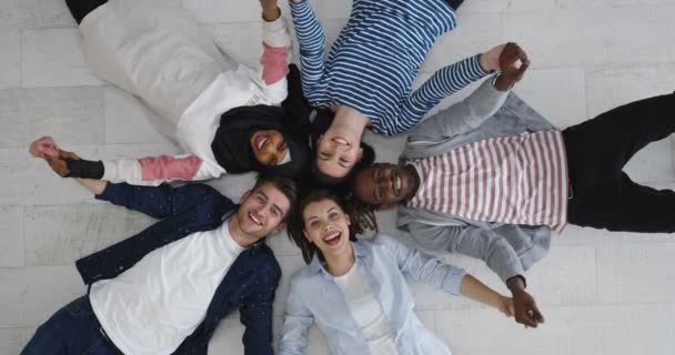 Multiethnische Freundesgruppe im Kreis auf dem Boden liegend — Stockvideo