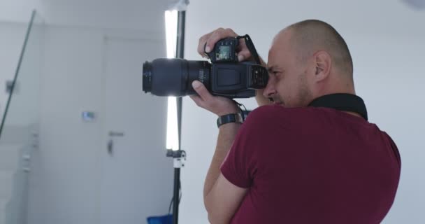 Professionele fotograaf in heldere studio tijdens fotosessie — Stockvideo