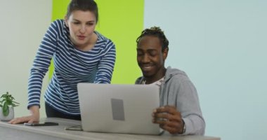 İş yerinin yakınında laptopla iş birliği yapan gülümseyen bir adam ve kadın.
