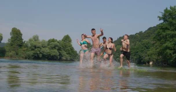 Sommerfreuden-Gruppe fröhlicher Freunde, die Spaß beim Laufen und Planschen auf dem Fluss haben — Stockvideo