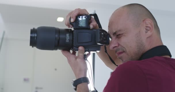 Profesionální fotograf ve světlém studiu během focení — Stock video