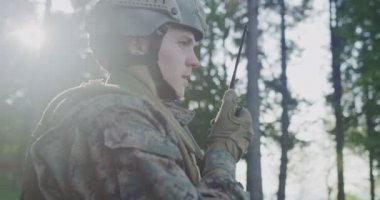 Ormandaki askerin portresi savaşa hazırlanıyor, silah ve iletişim teknolojisi kullanıyor.