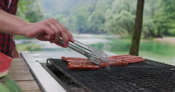 在河畔的野外烧烤时，近距离拍摄的人在烧烤时做饭的镜头，以及在大自然中预祝晚餐的镜头 — 图库视频影像