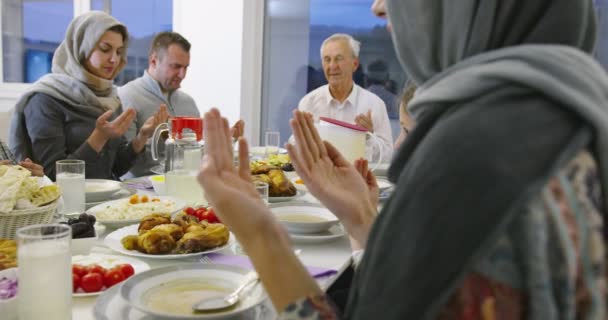 现代多民族穆斯林家庭在家里举行的拉马丹宴会上一起享用花蜜晚餐之前祈祷 — 图库视频影像