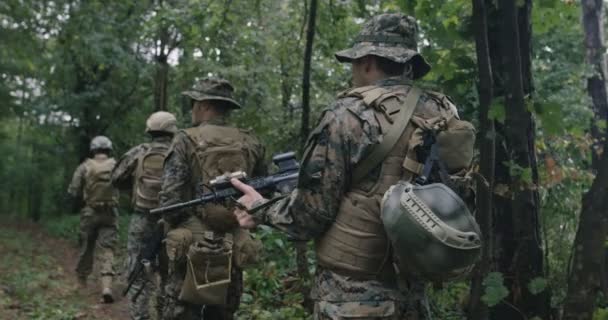 Voll ausgerüstete Soldaten in Tarnung auf einer Aufklärungsmission, die sich durch dichten Wald bewegt — Stockvideo