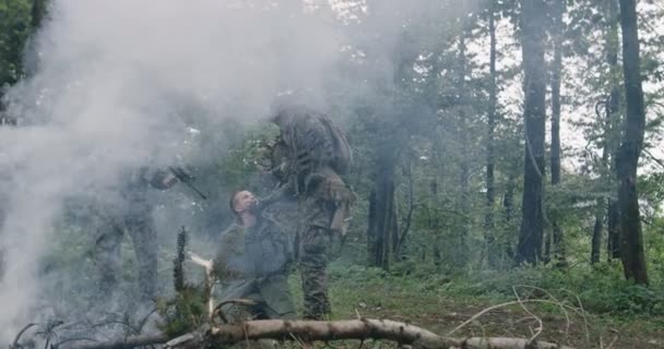 Askerler teröristleri yakalıyor ve arka planda dumanla yoğun bir ormanda anti-terörist askeri harekât yürütüyorlar. — Stok video